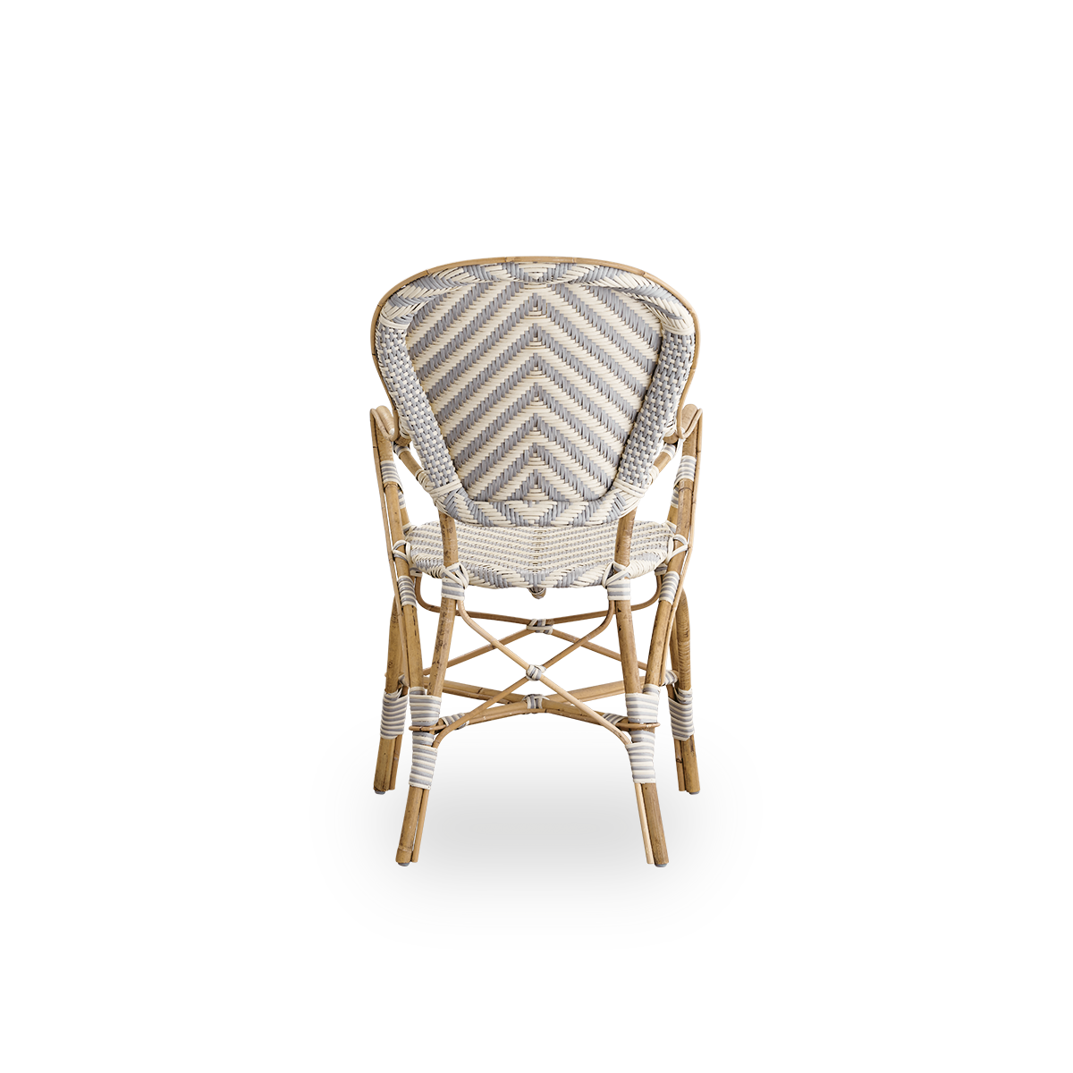 Vista desde atrás de la silla de comedor Isabell con reposabrazos. Estructura de ratán con asiento y respaldo de ArtFibre con un patrón de espiga en color marfil y gris. Inspirada en el diseño de bistró de los años 50.