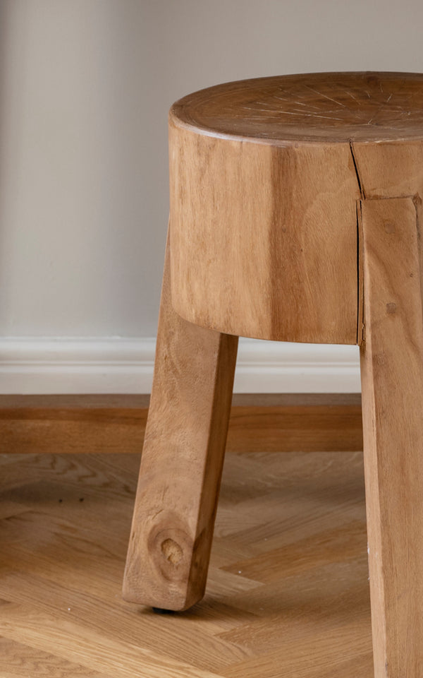 Esta es una imagen de detalle de Roger taburete en teak indoor. Detalle del asiento macizo de teca y tres patas angulares robustas.