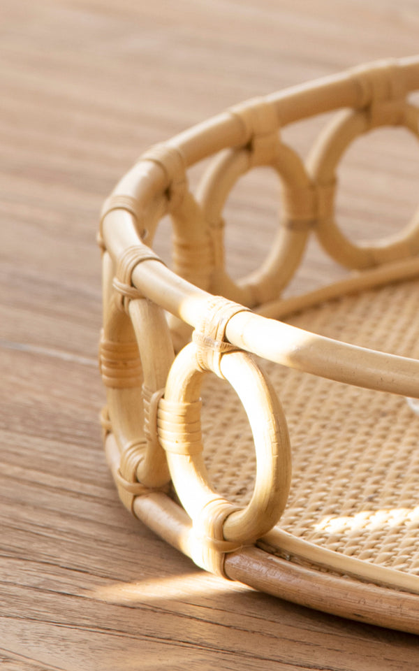 Esta es una imagen de detalle de Mira Tray i natural rattan. Detalle del borde circular de anillos y la base tejida de caña de la bandeja redonda.