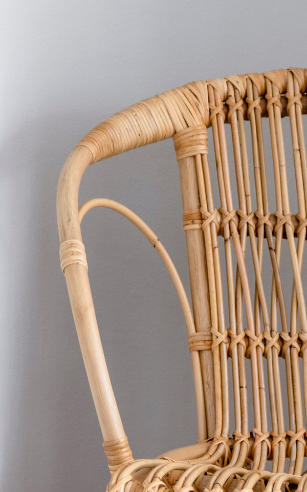 Esta es una imagen de detalle de Robert silla de comedor en polished natural rattan. Detalle del brazo curvo natural de ratán y respaldo de husillos.