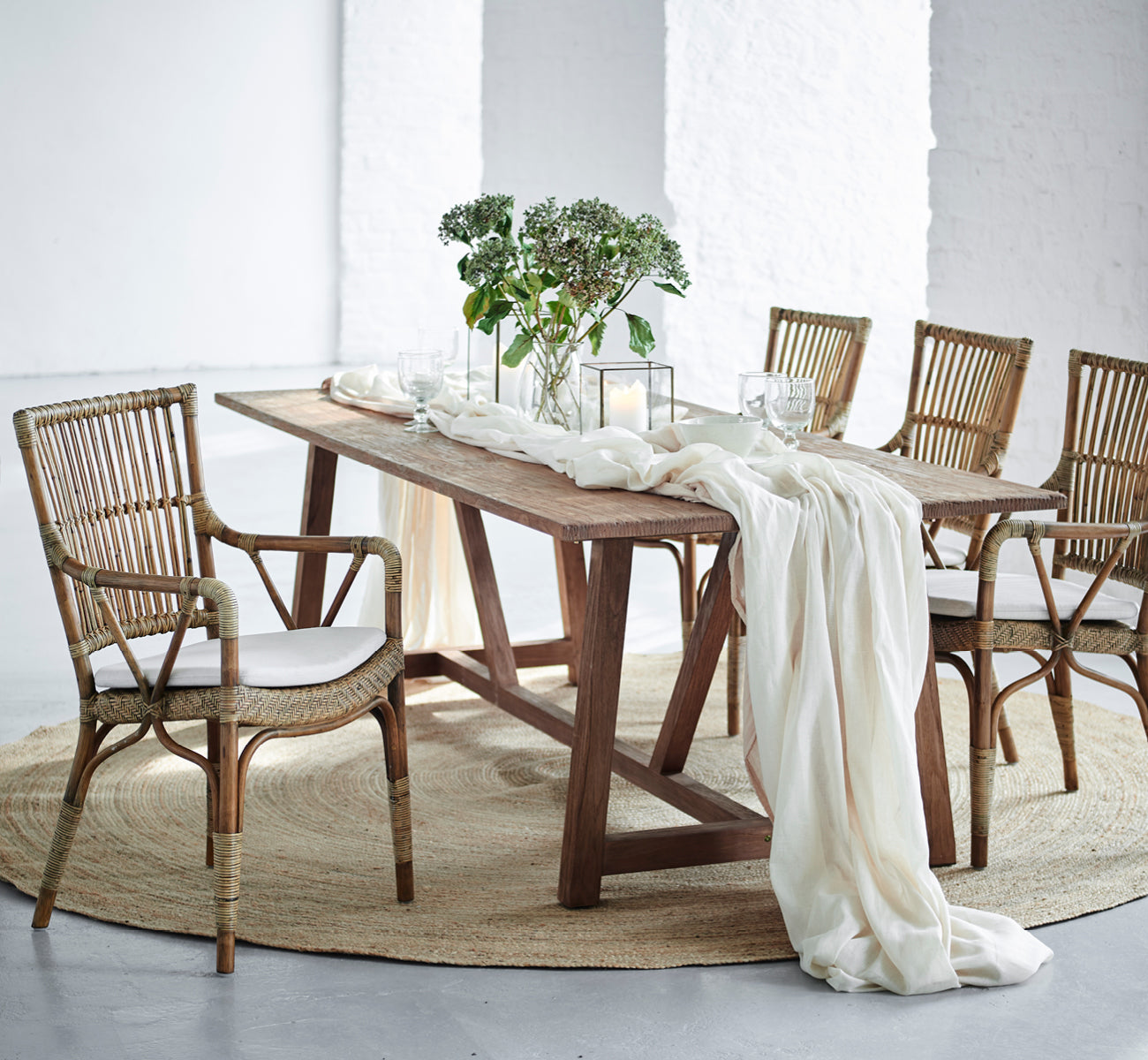 Esta es una imagen de estilo de vida de Piano silla de comedor en antique rattan. Alrededor de una mesa rústica de madera con camino de lino y velas.