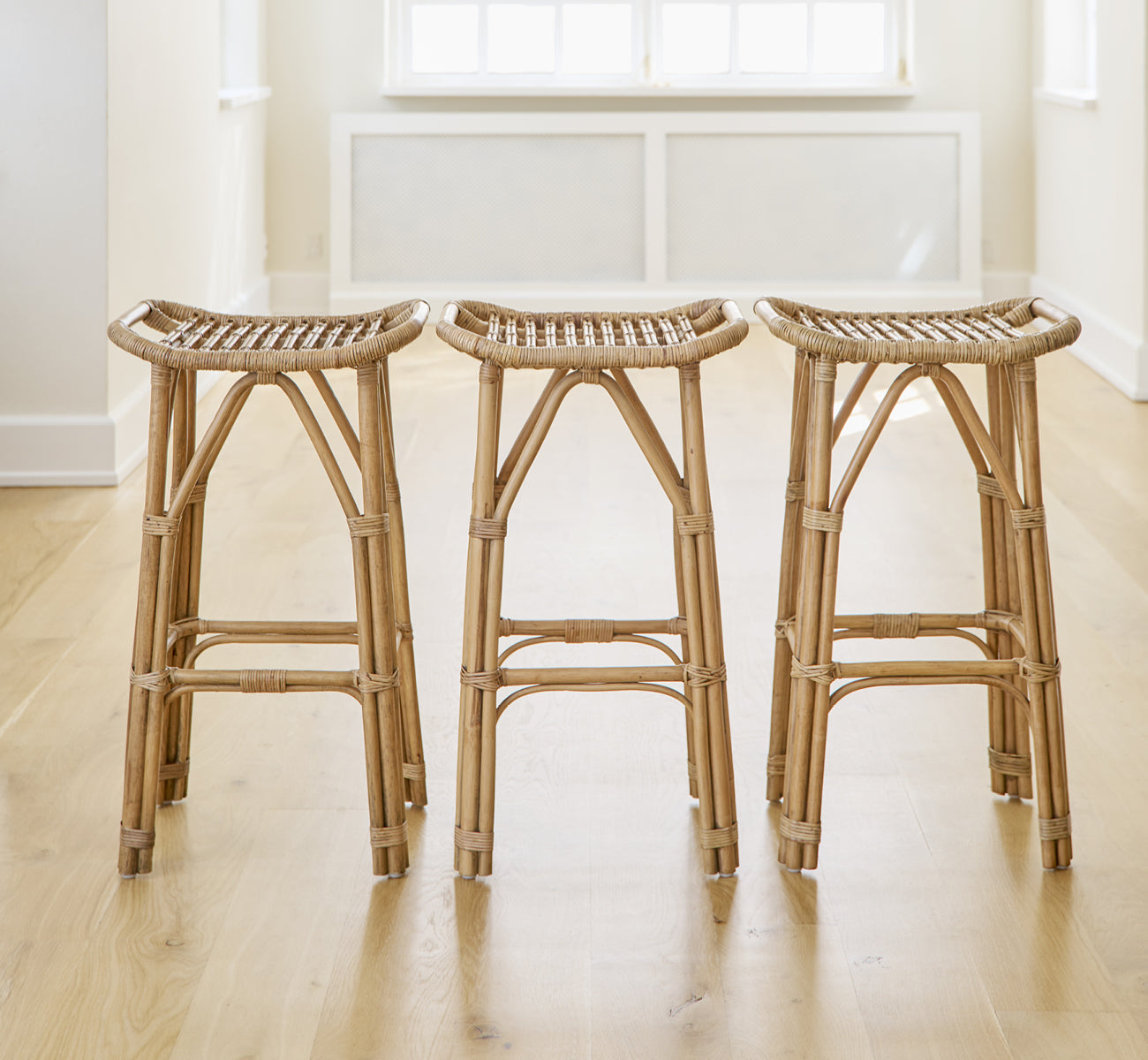 Esta es una imagen de estilo de vida de Salsa taburete de bar en antique rattan. Un par colocadas contra una pared blanca sobre suelo de parqué en espiga.