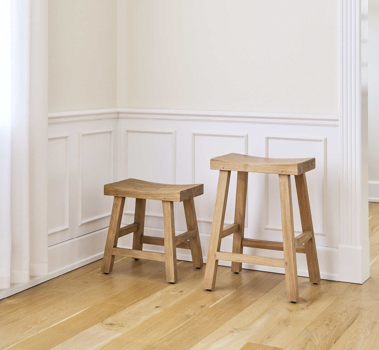 Esta es una imagen de estilo de vida de Charles taburete en teak indoor, en un interior blanco y luminoso con revestimiento de pared y parqué en.