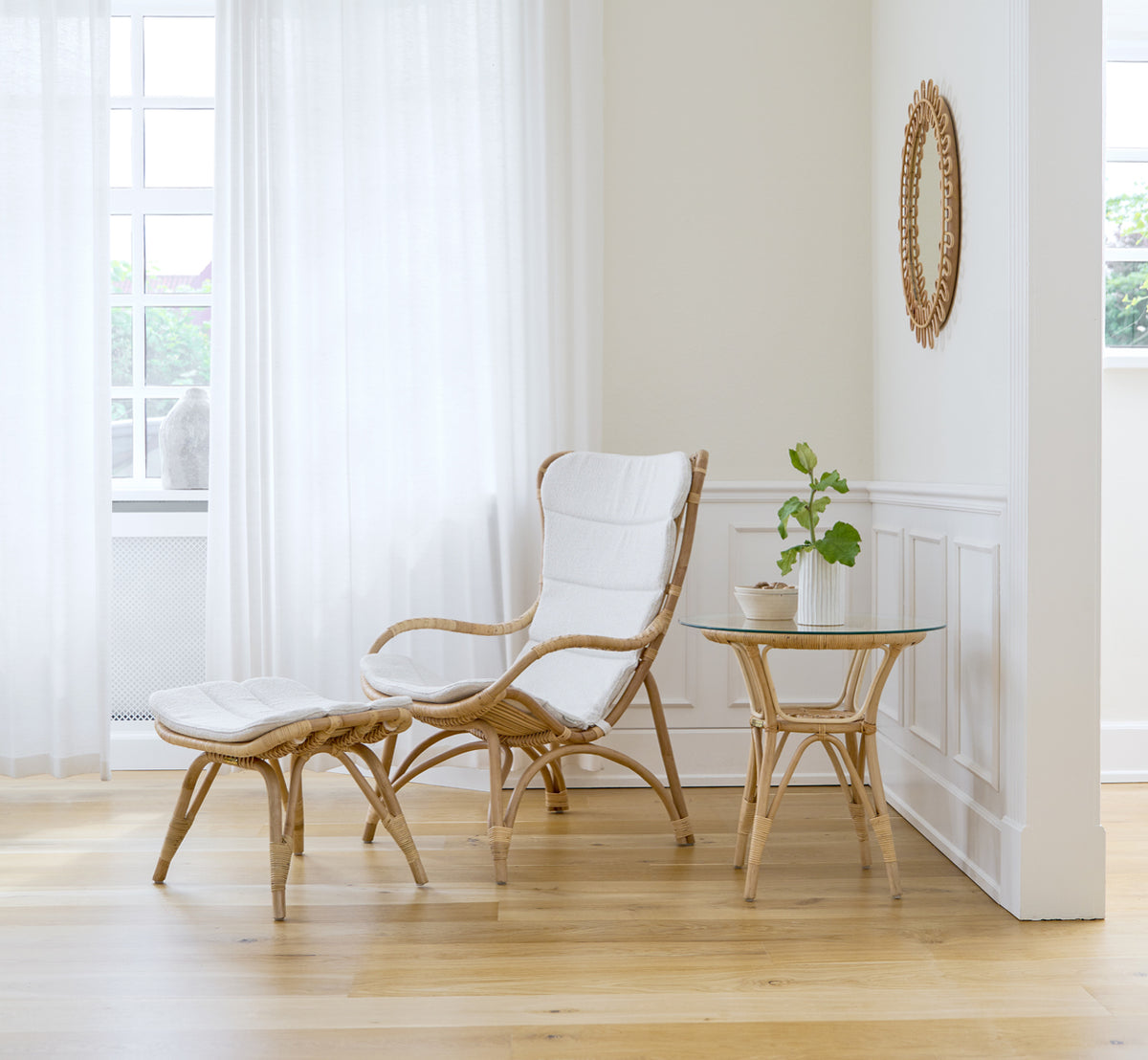 Esta es una imagen de estilo de vida de Monet Lounge Chair i natural rattan. En una habitación con paredes rosa, suelo en espiga y carrito de ratán.