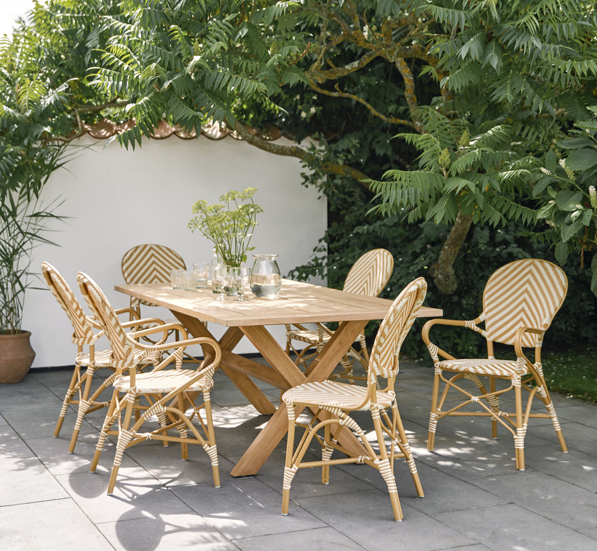 Esta es una imagen de estilo de vida de Isabell en almond aluminium frame Chevron Honey Ivory ArtFibre, en un exuberante patio de jardín con suelo de.