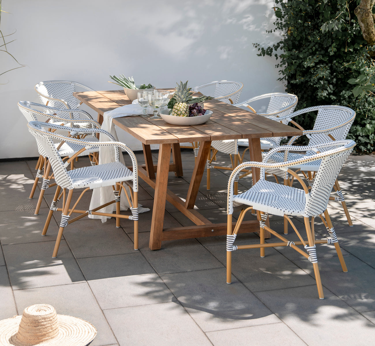 Esta es una imagen de estilo de vida de Madeleine silla de comedor exterior en almond aluminium frame white w cappuccino dot ArtFibre. Comedor de jardín con mesa de teca.