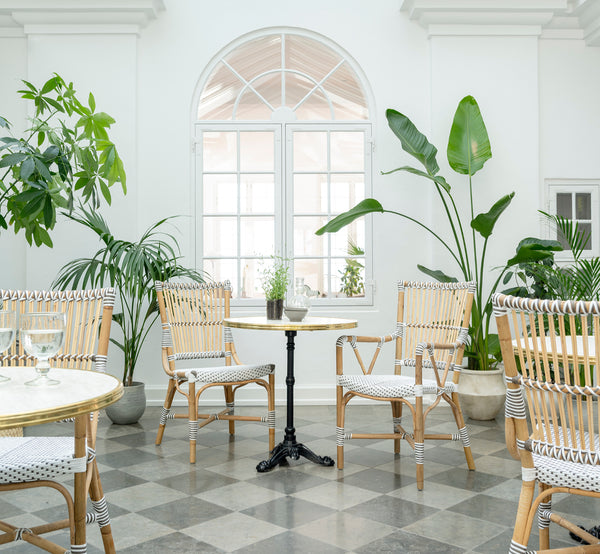 Esta es una imagen de estilo de vida de Monique sillón de comedor en white w cappuccino dot artfibre skin on rattan frame. Estilizado en un interior luminoso.