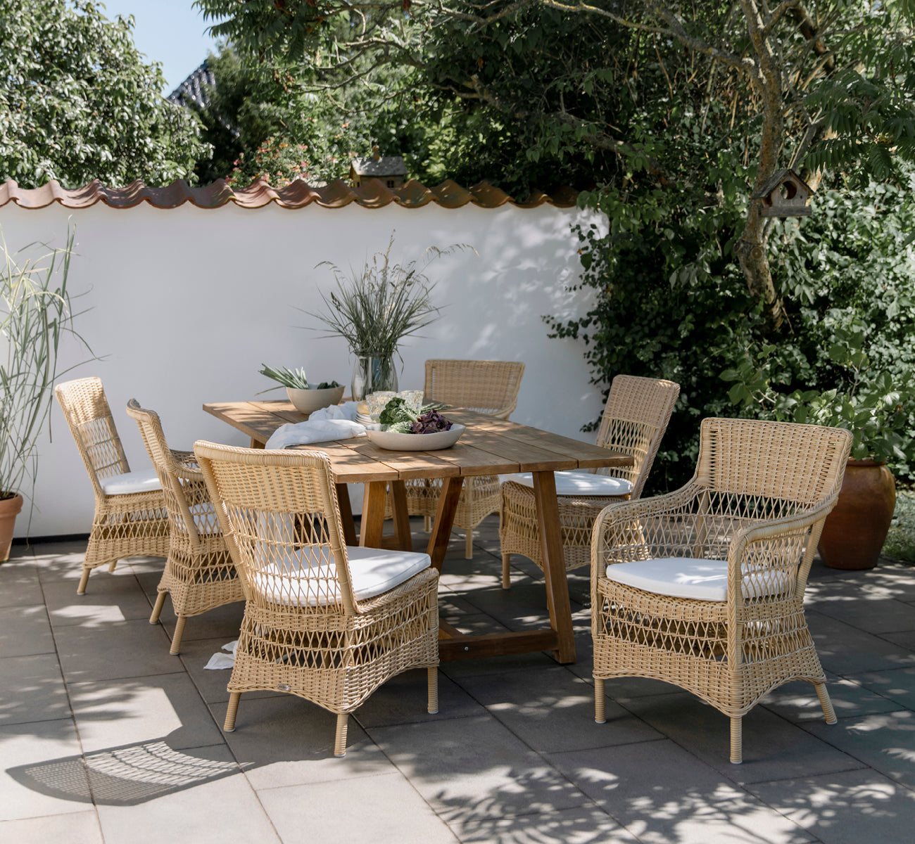 Esta es una imagen de estilo de vida de Marie sillón exterior en natural artfibre aluminium. Estilizado en un interior luminoso.