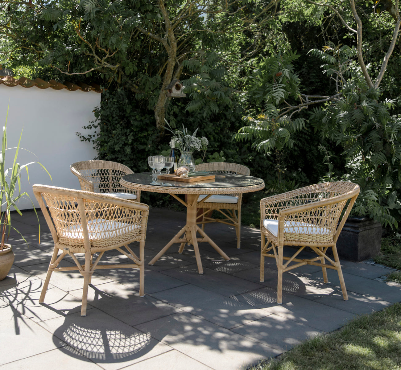 Esta es una imagen de estilo de vida de Emma silla de comedor exterior en natural ArtFibre Aluminium, en una terraza costera luminosa con techo de.