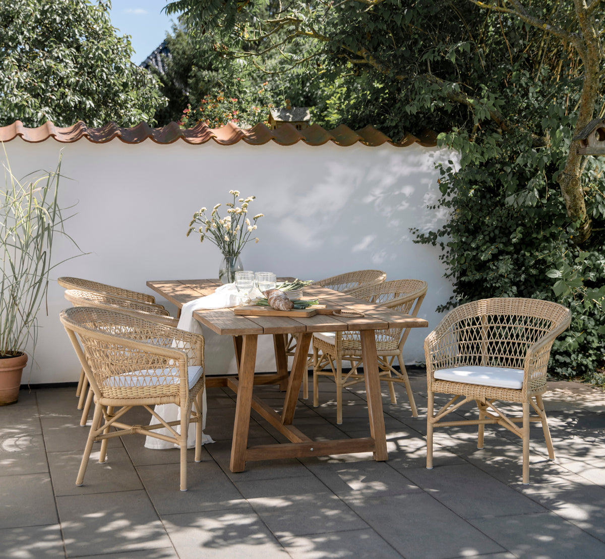 Esta es una imagen de estilo de vida de Emma silla de comedor exterior en natural ArtFibre Aluminium, en una terraza costera luminosa con techo de.