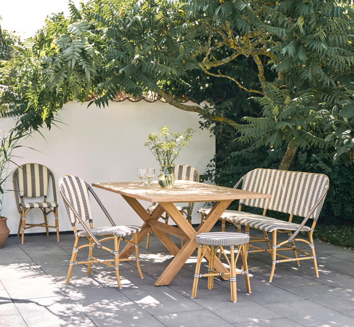 Esta es una imagen de estilo de vida de Colonial mesa 160 en outdoor Teak, en una terraza junto a la playa con cubierta de madera blanca y vistas al.