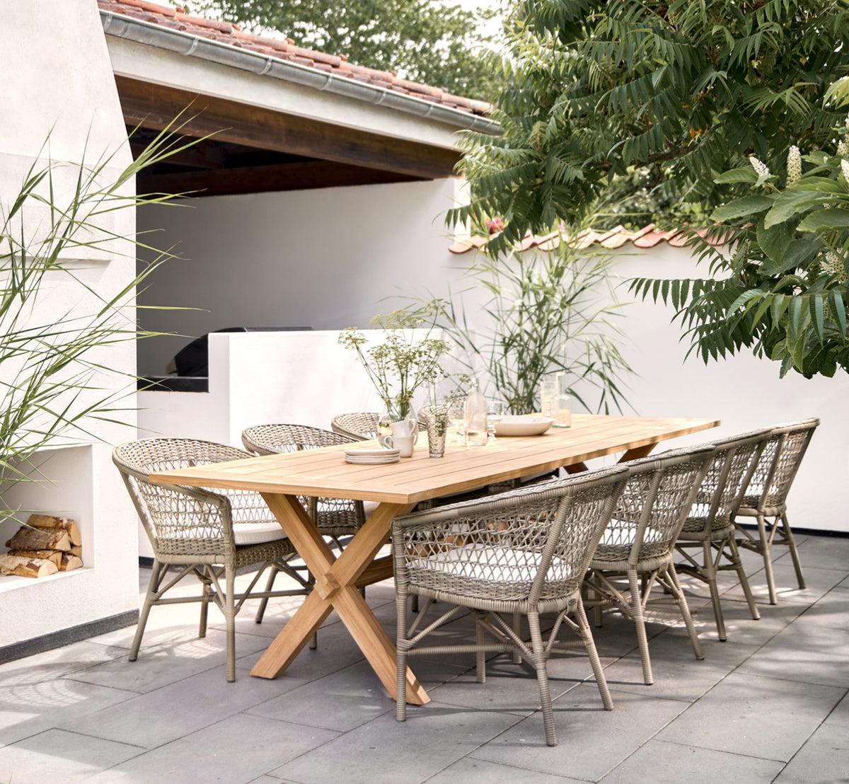 Esta es una imagen de estilo de vida de Colonial mesa 300 en outdoor Teak, en una terraza junto a la playa con cubierta de madera blanca y vistas al.