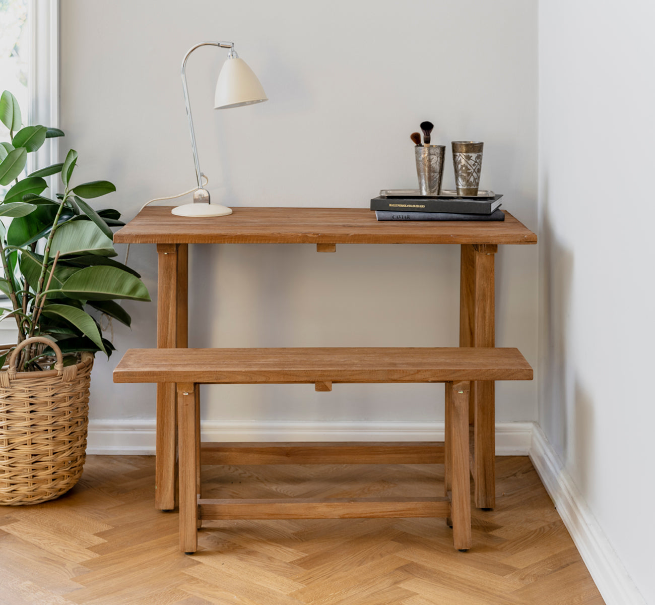 Esta es una imagen de estilo de vida de Lucas Teak escritorio en teak indoor. Estilizado con un banco a juego, lámpara de escritorio y libros en un rincón acogedor.