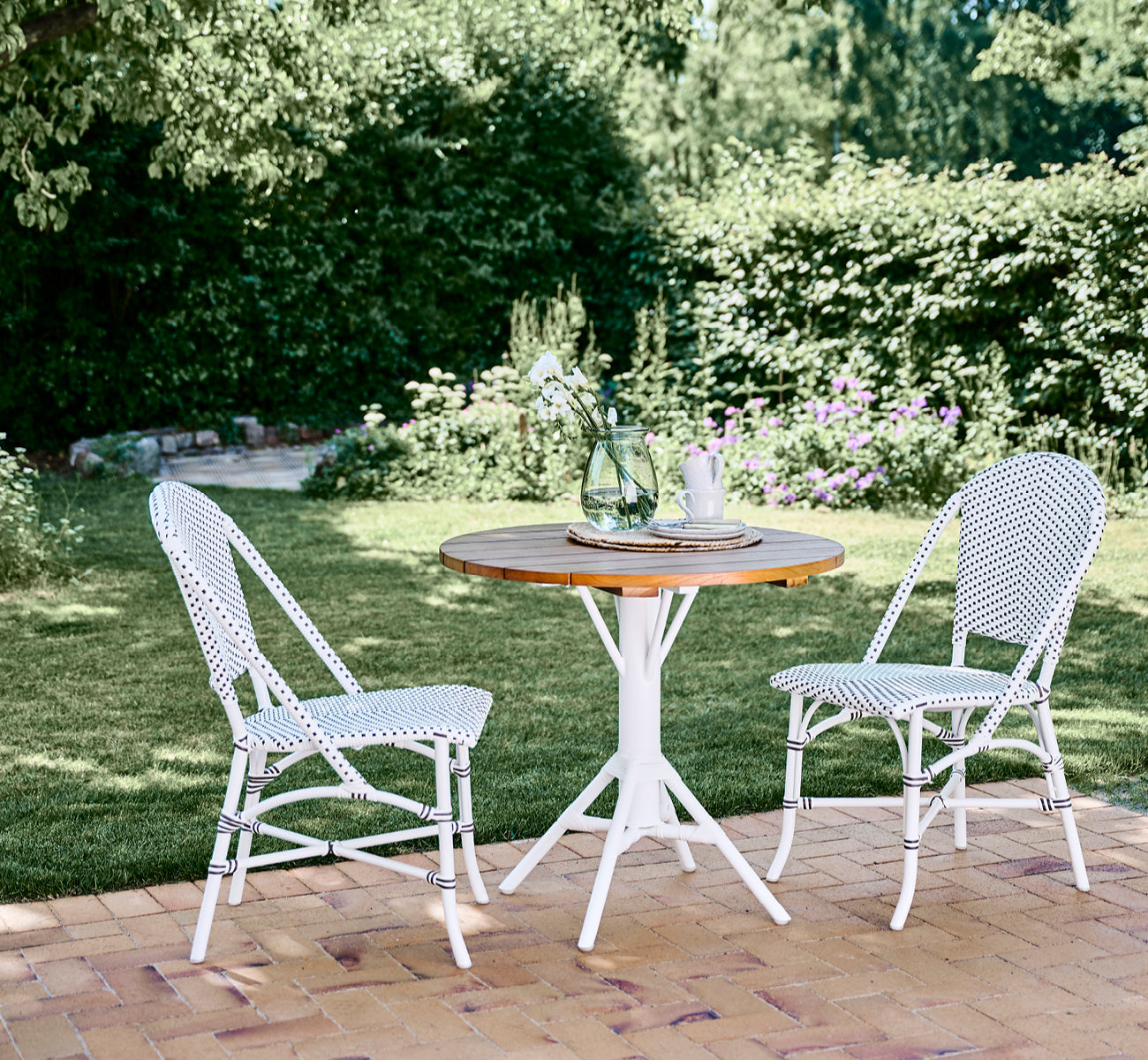 Esta es una imagen de estilo de vida de Nicole Cafe Table i white aluminium frame white ArtFibre. En un pabellón de playa con sillones Piano.
