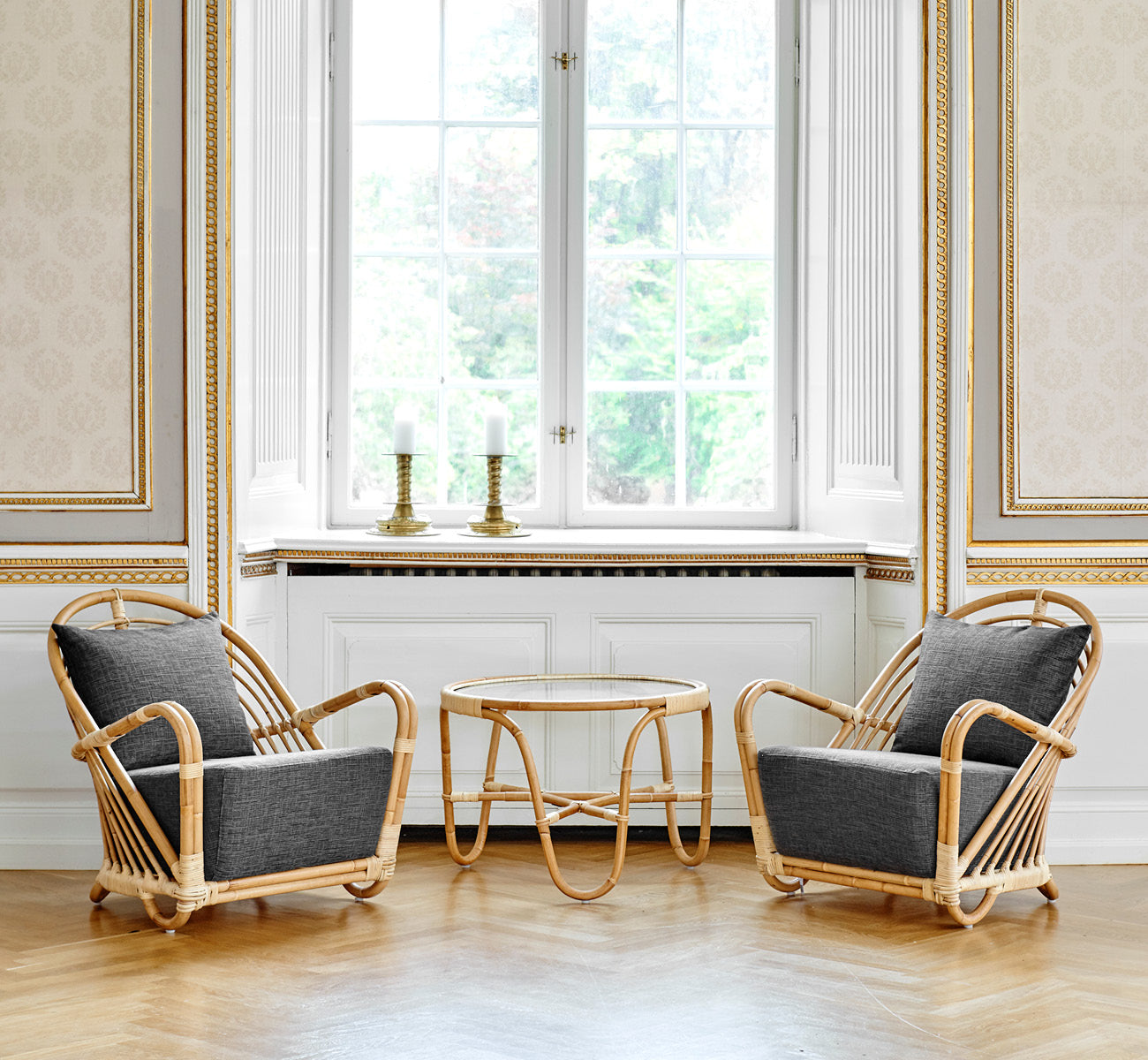 Esta es una imagen de estilo de vida de Charlottenborg sillón lounge en polished Natural Rattan, en un elegante interior clásico con elaboradas.