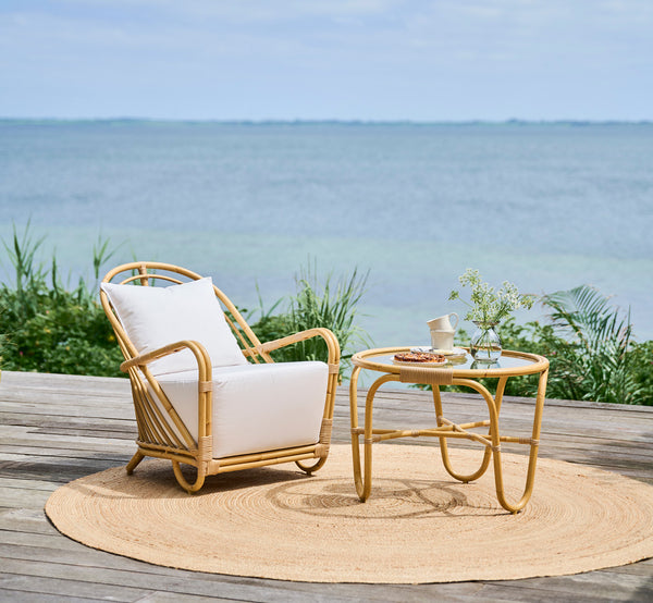 Esta es una imagen de estilo de vida de Charlottenborg mesa de centro exterior en natural Aluminium ArtFibre, en una terraza de madera al aire libre.