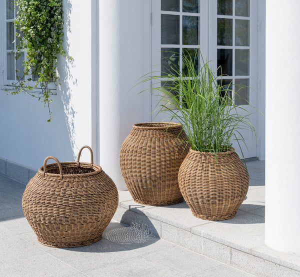 Esta es una imagen de estilo de vida de Ellis cesta en chestnut core weave ArtFibre Aluminium, en un patio exterior soleado con pared blanca y suelo.