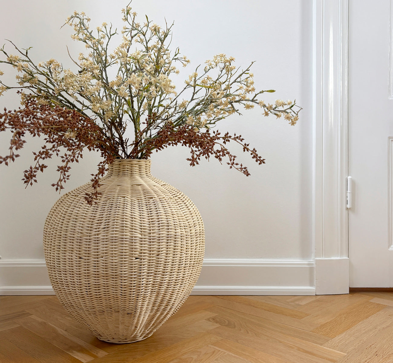 Esta es una imagen de estilo de vida de Flumen cesta en natural core weave iron frame, en un interior blanco y luminoso con revestimiento de pared,.