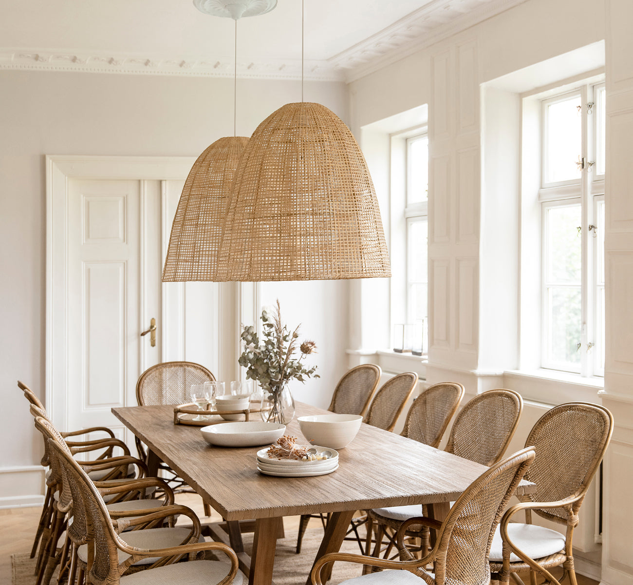 Esta es una imagen de estilo de vida de Showroom pantalla de lámpara en natural core weave artfibre & aluminium. Colgada sobre una mesa de comedor puesta en una habitación luminosa.