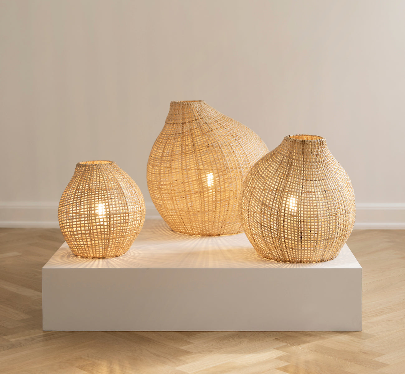 Esta es una imagen de estilo de vida de Figura pantalla de pie en light natural weave rattan, expuesto sobre una plataforma blanca ante un fondo de.