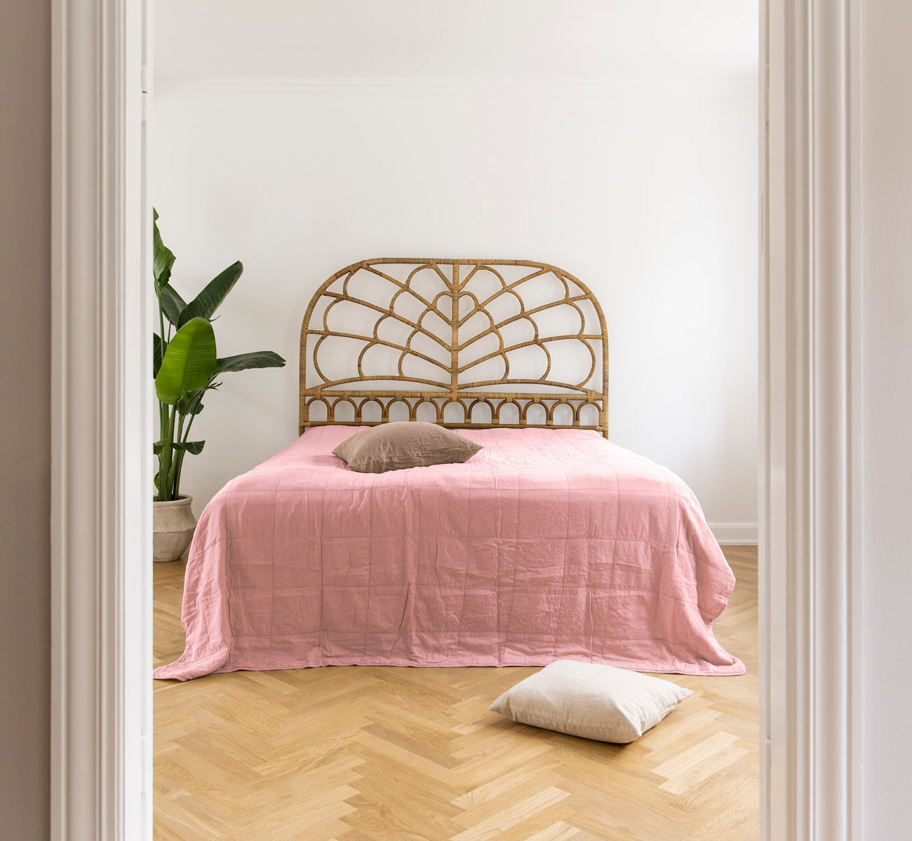 Esta es una imagen de estilo de vida de CTE058MR colcha en misty Rose Cotton, en un dormitorio sereno con decoración neutra y parqué en espiga.