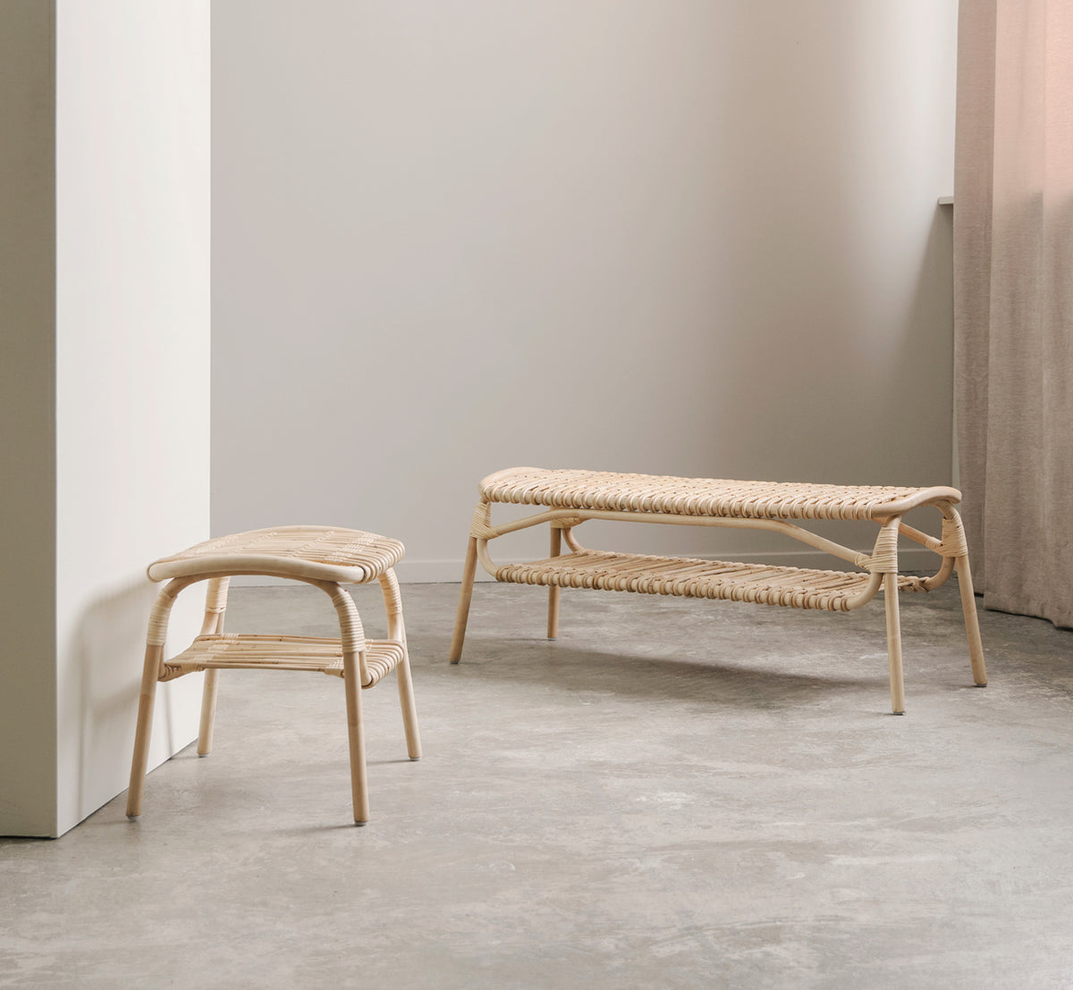 Esta es una imagen de estilo de vida de Machiya banco en natural skin on rattan. Sala minimalista con suelo de hormigón, taburete de ratán y cortina de lino.
