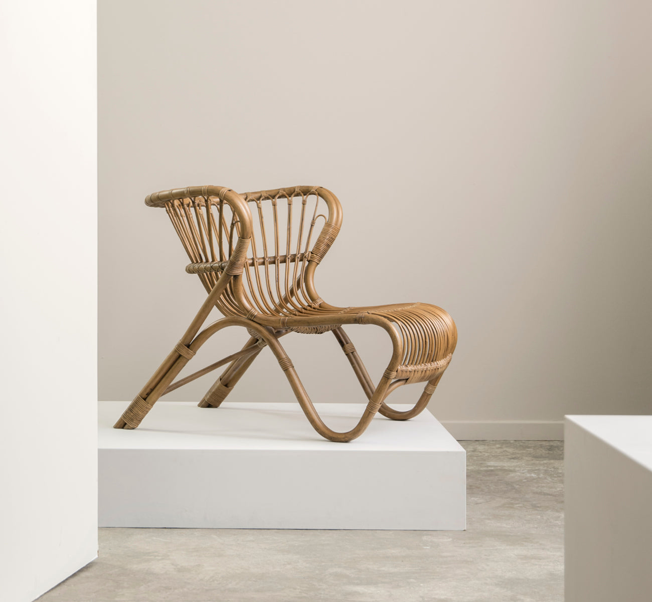 Esta es una imagen de estilo de vida de Fox sillón lounge en polished Antique Rattan, en un interior cálido con lambrisado ocre y parqué oscuro en.