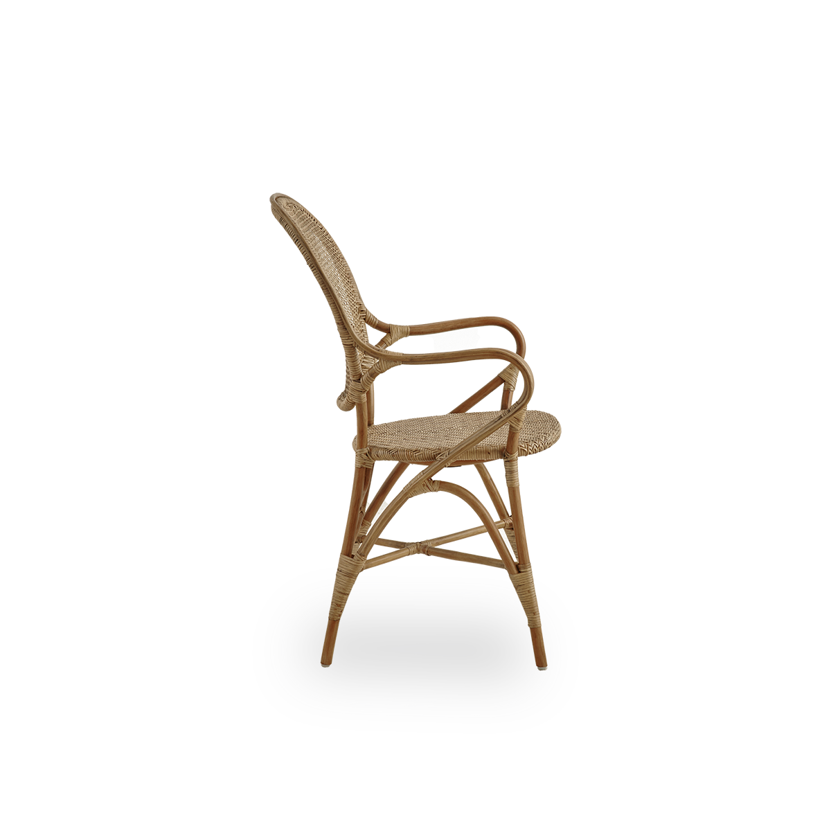 Vista lateral del sillón de comedor Rossini en color marrón antiguo. Elegante silla de mimbre con respaldo redondo y reposabrazos de diseño sencillo. Hecha a mano con ratán de alta calidad.