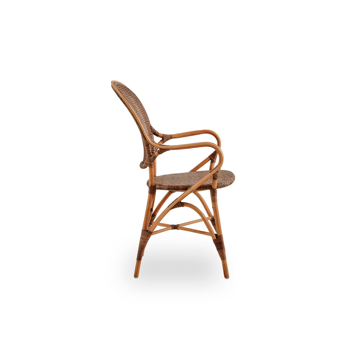 Vista lateral del sillón de comedor Rossini en color cereza. Elegante silla de mimbre con respaldo redondo y reposabrazos de diseño sencillo. Hecha a mano con ratán de alta calidad.