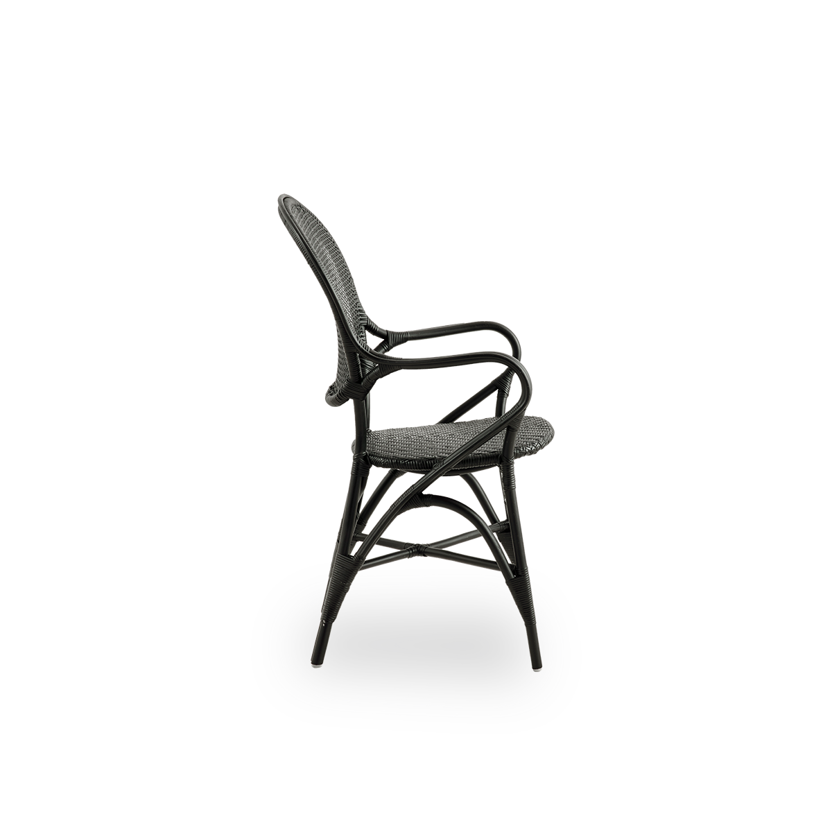 Vista lateral del sillón de comedor Rossini en color negro. Elegante silla de mimbre con respaldo redondo y reposabrazos de diseño sencillo. Hecha a mano con ratán de alta calidad.