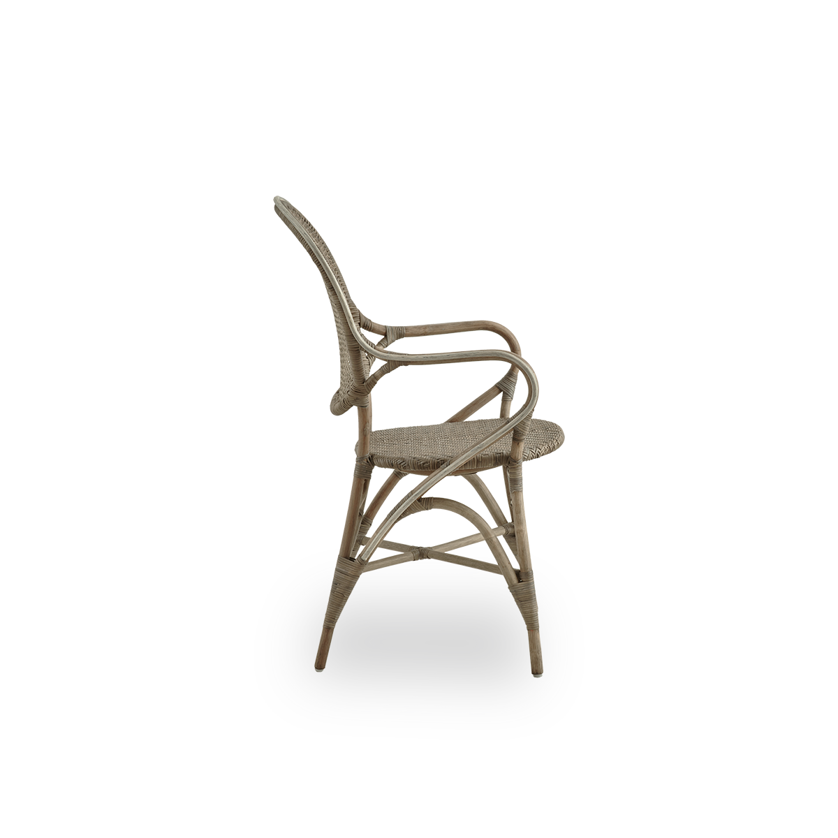 Vista lateral del sillón de comedor Rossini en color taupe. Elegante silla de mimbre con respaldo redondo y reposabrazos de diseño sencillo. Hecha a mano con ratán de alta calidad.