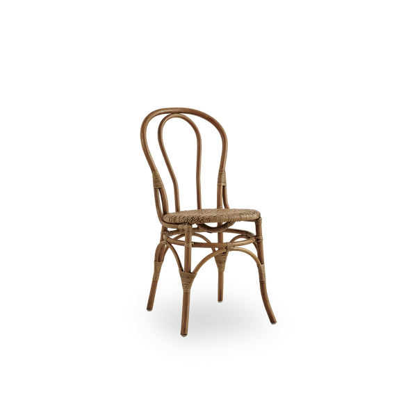 Vista lateral de la silla de comedor Lulu en color Antique Brown, hecha a mano con ratán de alta calidad de Indonesia. Diseño ligero y elegante con respaldo redondo y sencillo.