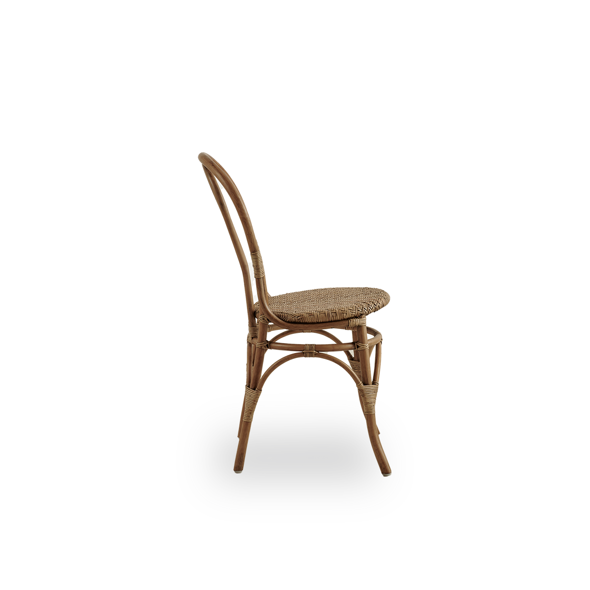 Vista lateral de la silla de comedor Lulu en color marrón antiguo, hecha a mano con ratán indonesio de alta calidad. Diseño ligero y elegante con respaldo redondo y sencillo.