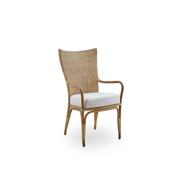 Vista lateral de la silla de comedor Melody con brazos en color ratán Antique, con respaldo alto completamente tejido en ratán y asiento acolchado.