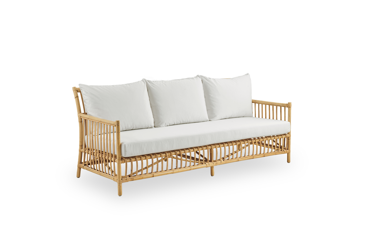 Vista lateral del sofá de mimbre Caroline de 3 plazas, diseño danés simple y elegante. Hecho a mano en ratán indonesio con detalles tejidos que crean una presencia acogedora y relajante.