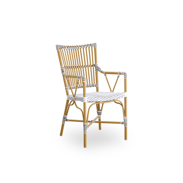 Vista lateral de la silla de comedor exterior Monique con brazos. Estructura de aluminio color almendra con asiento tejido en ArtFibre blanco con puntos marrones. Inspirada en el diseño de bistró de los años 50.
