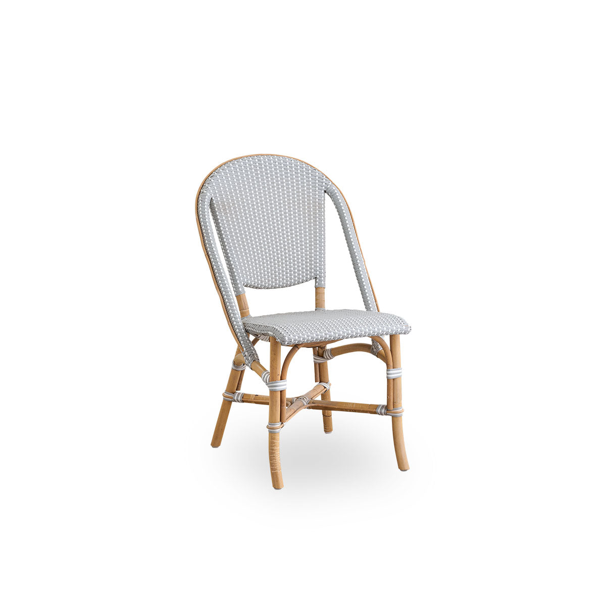 Vista lateral de la silla de comedor Sofie de ratán, inspirada en el estilo de café francés. Estructura de ratán con asiento y respaldo completamente tejidos, hechos a mano en ArtFibre gris con patrón de puntos blancos. Silla bistró de ratán apilable.