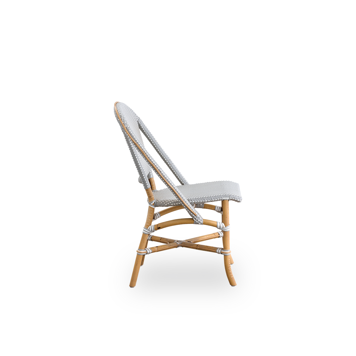 Vista lateral de la silla de comedor Sofie de ratán, inspirada en el estilo de café francés. Estructura de ratán con asiento y respaldo completamente tejidos a mano en ArtFibre gris con patrón de puntos blancos. Silla de bistró de ratán apilable.