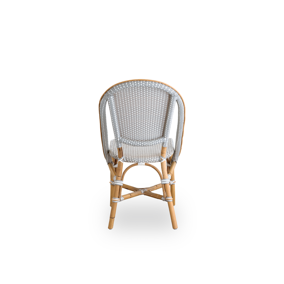 Vista trasera sencilla de la silla de comedor Sofie de ratán, inspirada en el estilo de los cafés franceses. Estructura de ratán con asiento y respaldo completamente tejidos, hechos a mano en ArtFibre en color gris con patrón de puntos blancos. Silla bist