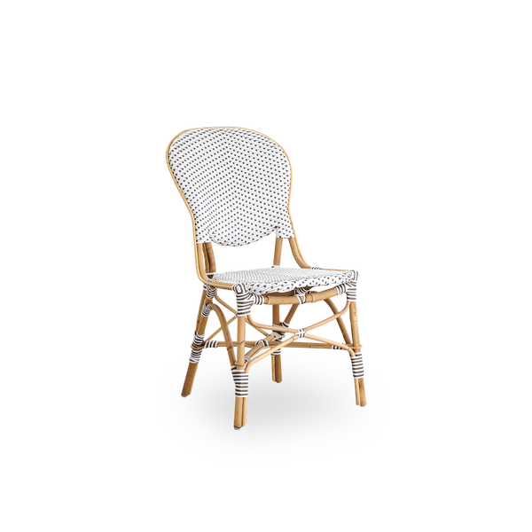 Vista lateral de la silla de comedor Isabell. Estructura de ratán con asiento y respaldo en ArtFibre blanco con puntos marrones. Inspirada en el diseño de bistró de los años 50.
