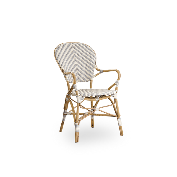 Vista lateral de la silla de comedor Isabell con reposabrazos. Estructura de ratán con asiento y respaldo en ArtFibre con patrón de espiga en marfil y gris. Inspirada en el diseño de bistró de los años 50.