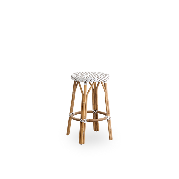 Vista lateral del taburete de barra Simone, altura 68 cm. Estructura de ratán con reposapiés y asiento redondo completamente tejido, hecho a mano en ArtFibre blanco con patrón de puntos marrones. Taburete apilable.