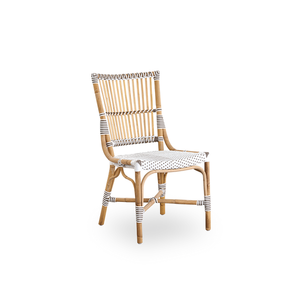 Vista lateral de la silla de comedor Monique. Estructura de ratán con asiento tejido en ArtFibre blanco con puntos marrones. Inspirada en el diseño de bistró de los años 50.