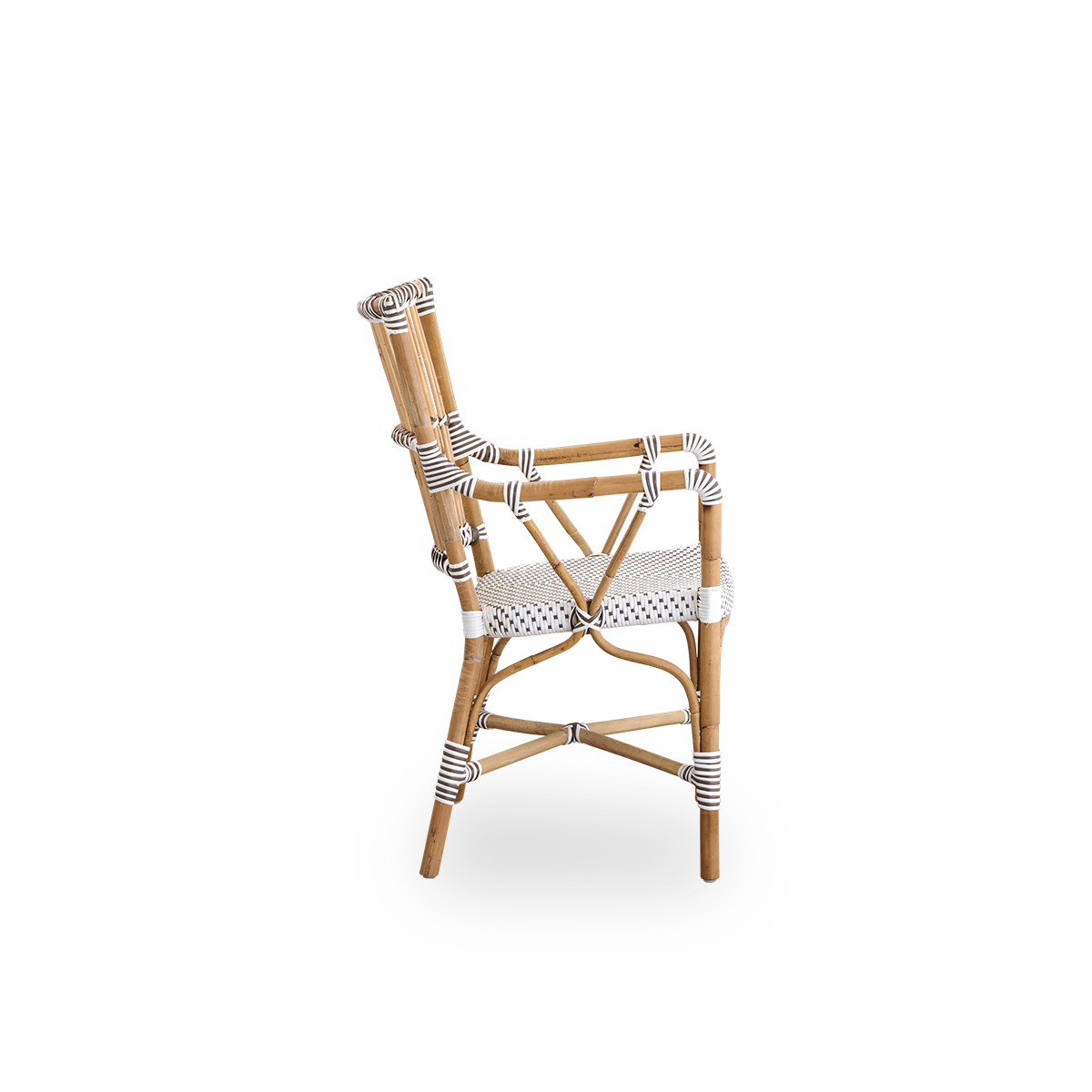 Vista lateral de la silla de comedor Monique con reposabrazos. Estructura de ratán con asiento tejido en ArtFibre blanco con puntos marrones. Inspirada en el diseño de bistró de los años 50.