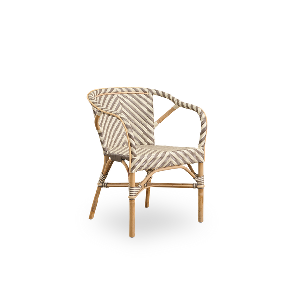 Vista lateral de la silla de comedor con brazos Madeleine. Estructura de ratán con asiento y respaldo tejidos en ArtFibre con patrón de espiga en marfil y marrón. Inspirada en el diseño de bistró de los años 50.