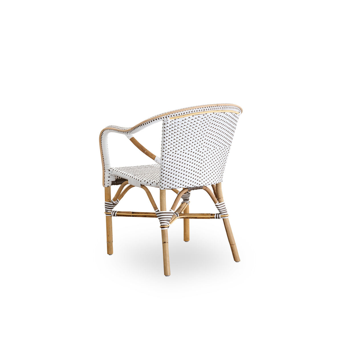 Vista trasera de la silla de comedor Madeleine con reposabrazos.
Estructura de ratán con asiento y respaldo tejidos en ArtFibre blanco con puntos marrones. Inspirada en el diseño de bistró de los años 50.
