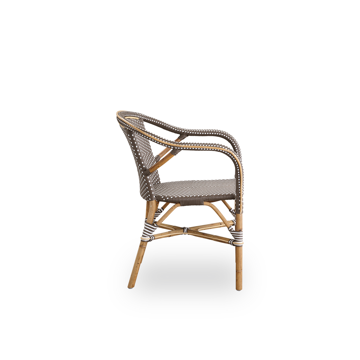 Vista lateral de la silla de comedor Madeleine con reposabrazos. Estructura de ratán con asiento y respaldo en ArtFibre marrón con puntos blancos. Inspirado en el diseño de bistró de los años 50.