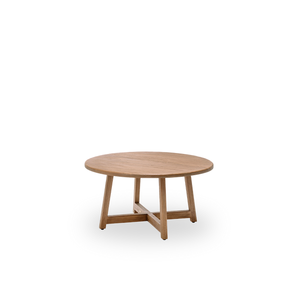 Vista lateral de la mesa de centro Aksel, Ø100 cm, en teca con superficie natural y patinada. Tratada en superficie para resaltar la veta natural de la madera, con un encantador aire rústico. Fabricada en teca certificada como Indonesian Legal Wood.