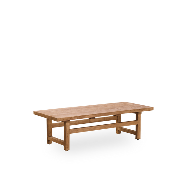 Vista lateral de la mesa de café Alfred, 140x55 cm, fabricada con madera legal de Indonesia, con teca patinada y acabado rústico, mostrando la madera natural y un diseño sólido.