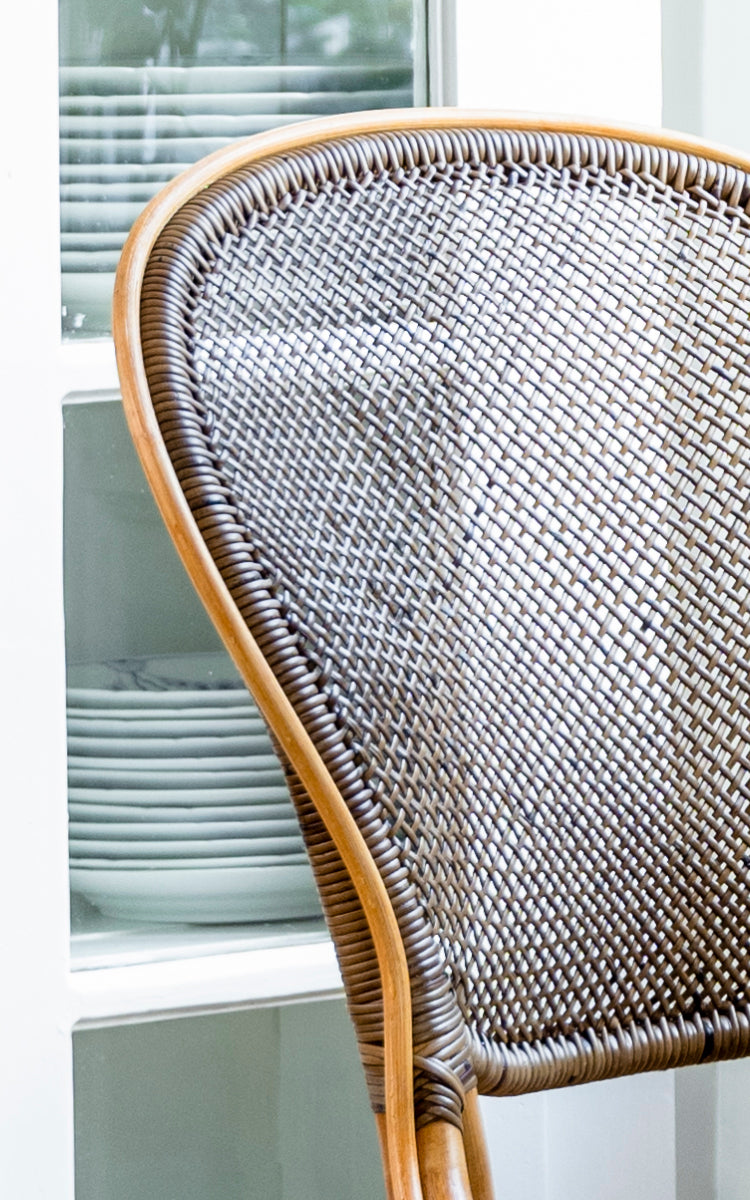 Esta es una imagen de detalle de Rossini silla de comedor en cherry rattan. Vista detallada del respaldo de tejido de caña cereza sobre armarios claros.